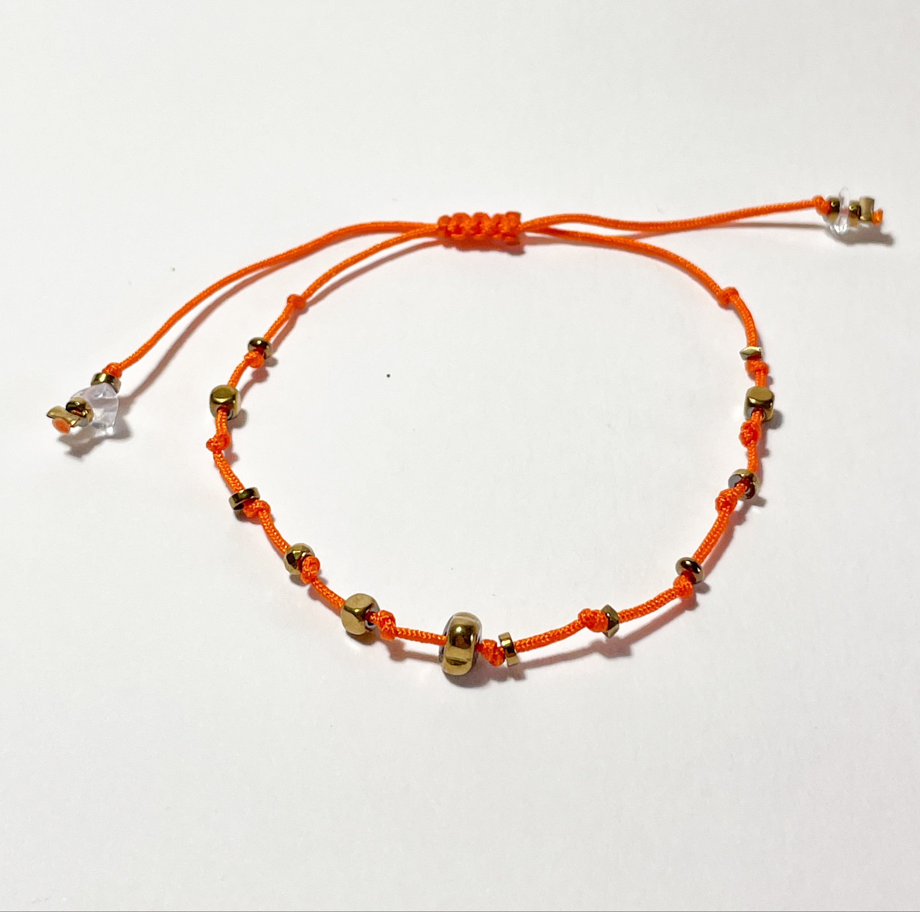 bracelet fin en hematite dorée, noeud coulissant orange